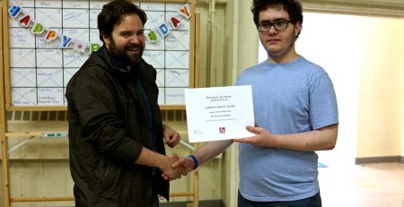 William Coons during his time at Franklin Academy, holding up an award certificate with one of his teachers.