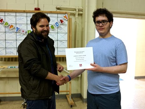 William Coons during his time at Franklin Academy, holding up an award certificate with one of his teachers.