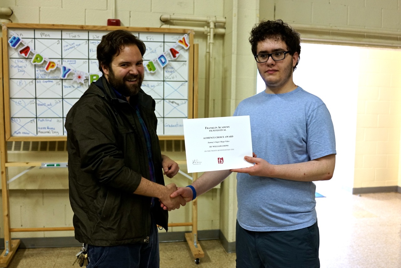 William Coons during his time at Franklin Academy, holding up an award certificate with one of his teachers.