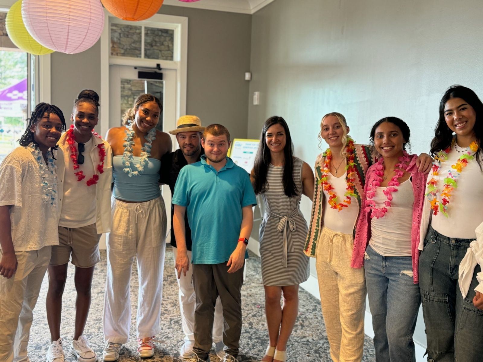 Kevin Coons, wearing a sky blue shirt, with the UConn women's basketball team, wearing leis.